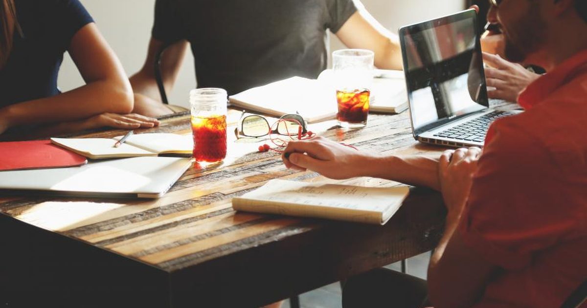 Equipo de trabajo reunido alrededor de una mesa con laptops