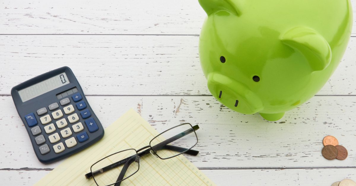 Alcancia, calculadora y monedas sobre un escritorio